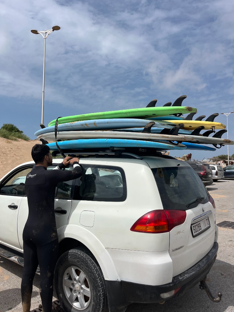 Surfer in wetsuit loading surfboards on a 4x4 before a Morocco surf trip from Essaouira