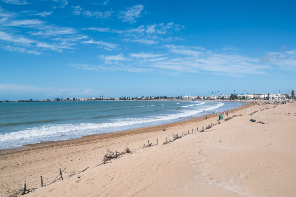 Diabat Beach surf Essaouira — wide sandy bay with Atlantic waves and city skyline in the distance