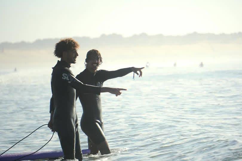 Two surfers in wetsuits scouting waves in the Atlantic off Essaouira, Morocco