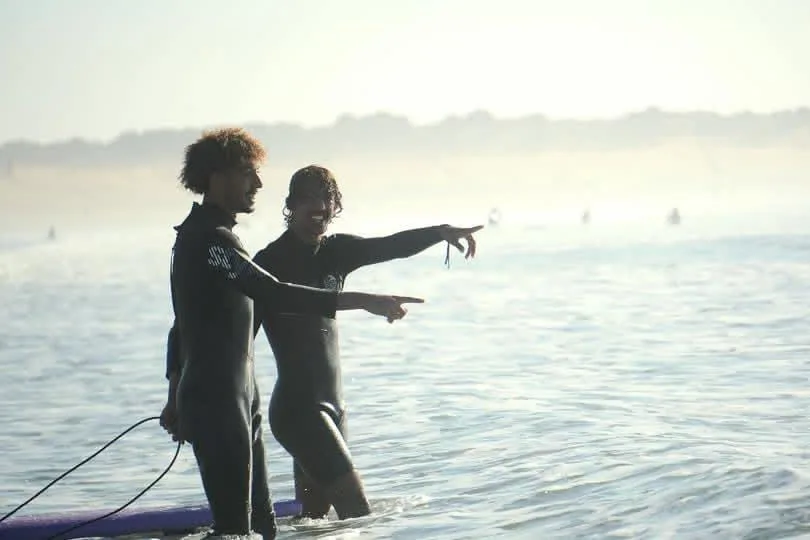 Two surfers in wetsuits scouting waves in the Atlantic off Essaouira, Morocco