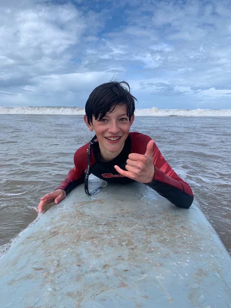Child surfer smiling on soft board Essaouira kids surf lesson