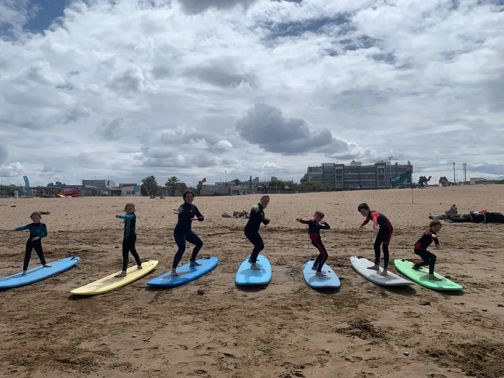Surf students practicing pop-up stance on boards on Essaouira beach