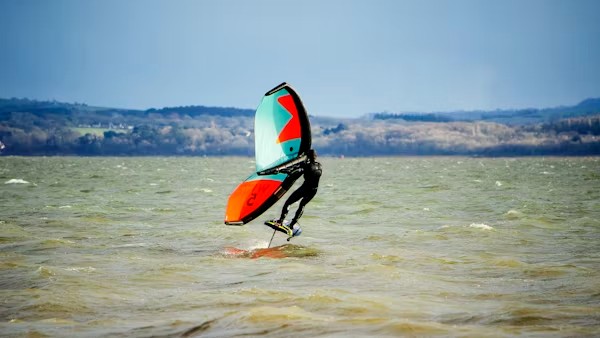 Wing foiler jumping above the water near Essaouira during a wing foil course session