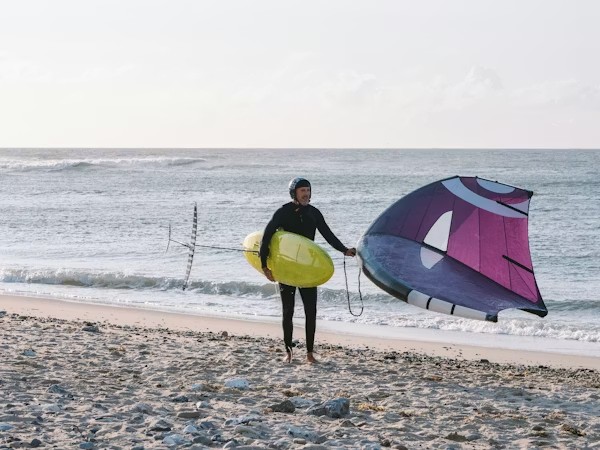Wing foiler on Essaouira beach with helmet, wing and foil board before a private lesson